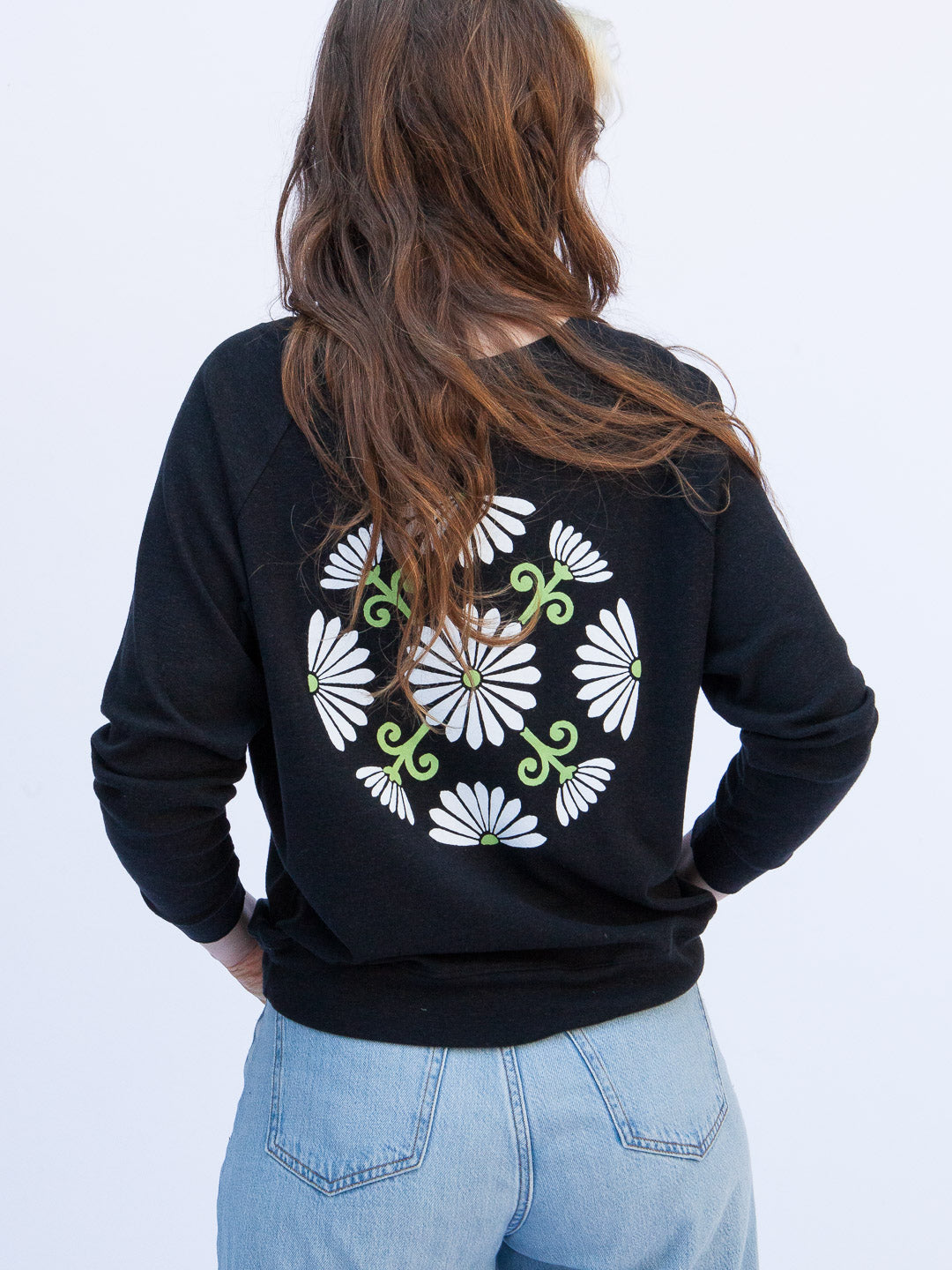 Person wearing a black sweatshirt with a floral design on the back against a white background