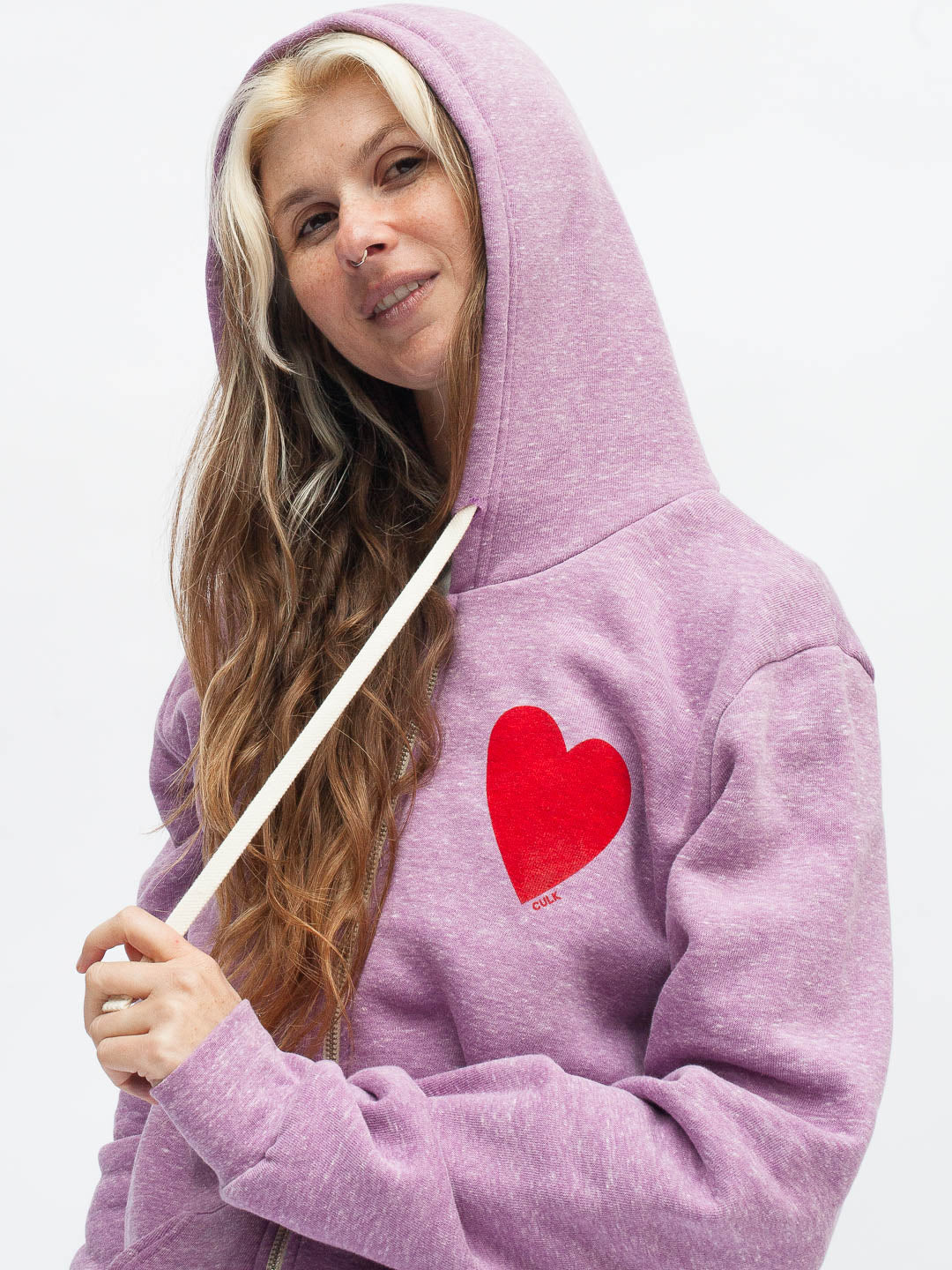 Person wearing a purple hoodie with a red heart design on a white background