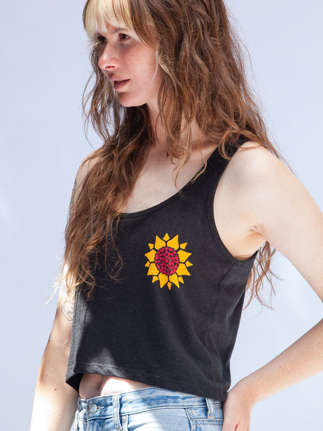 Woman wearing a black tank top with a sunflower design on a light gray background