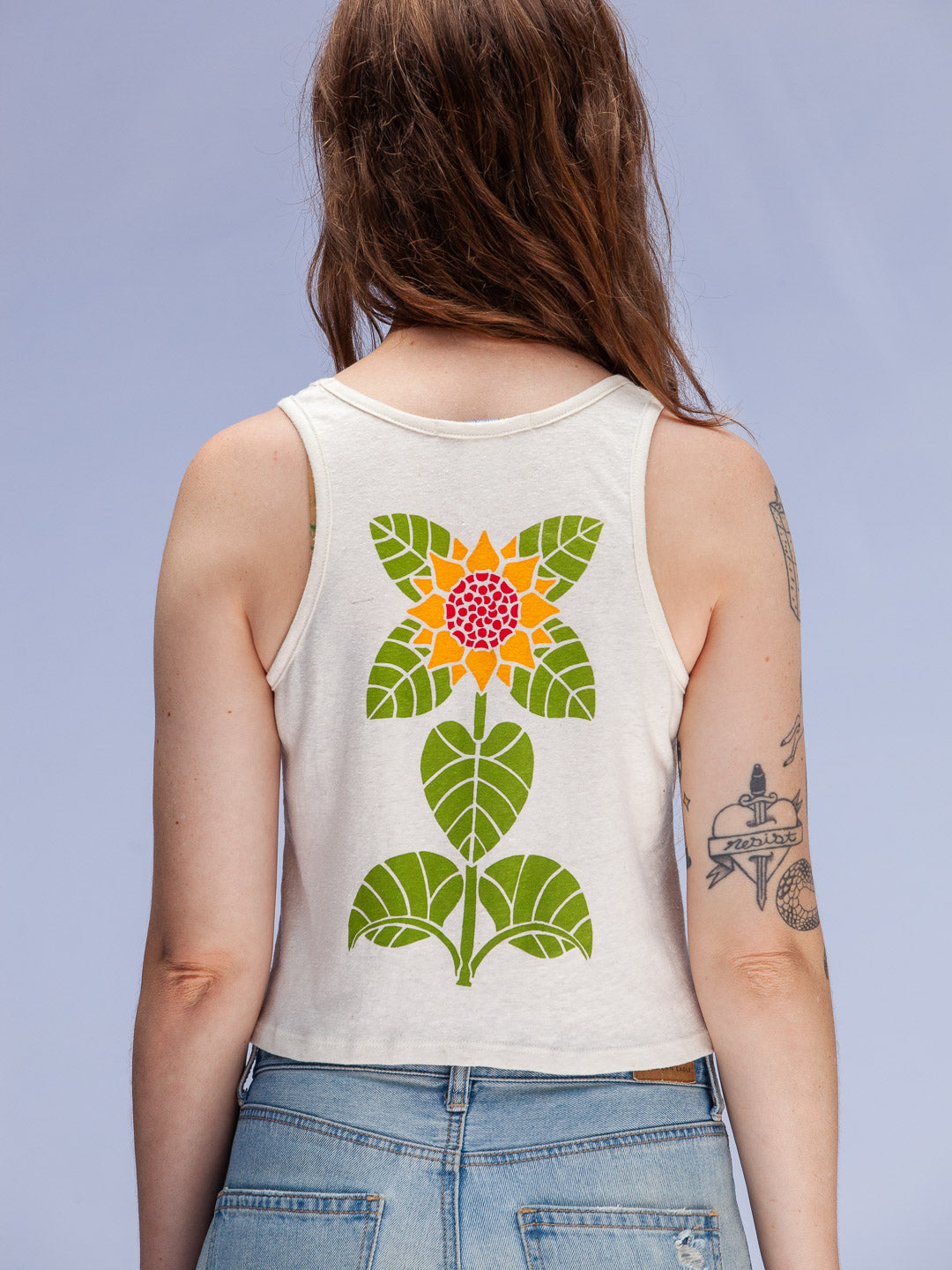 Person wearing a sleeveless shirt with a colorful floral design on the back against a light gray background