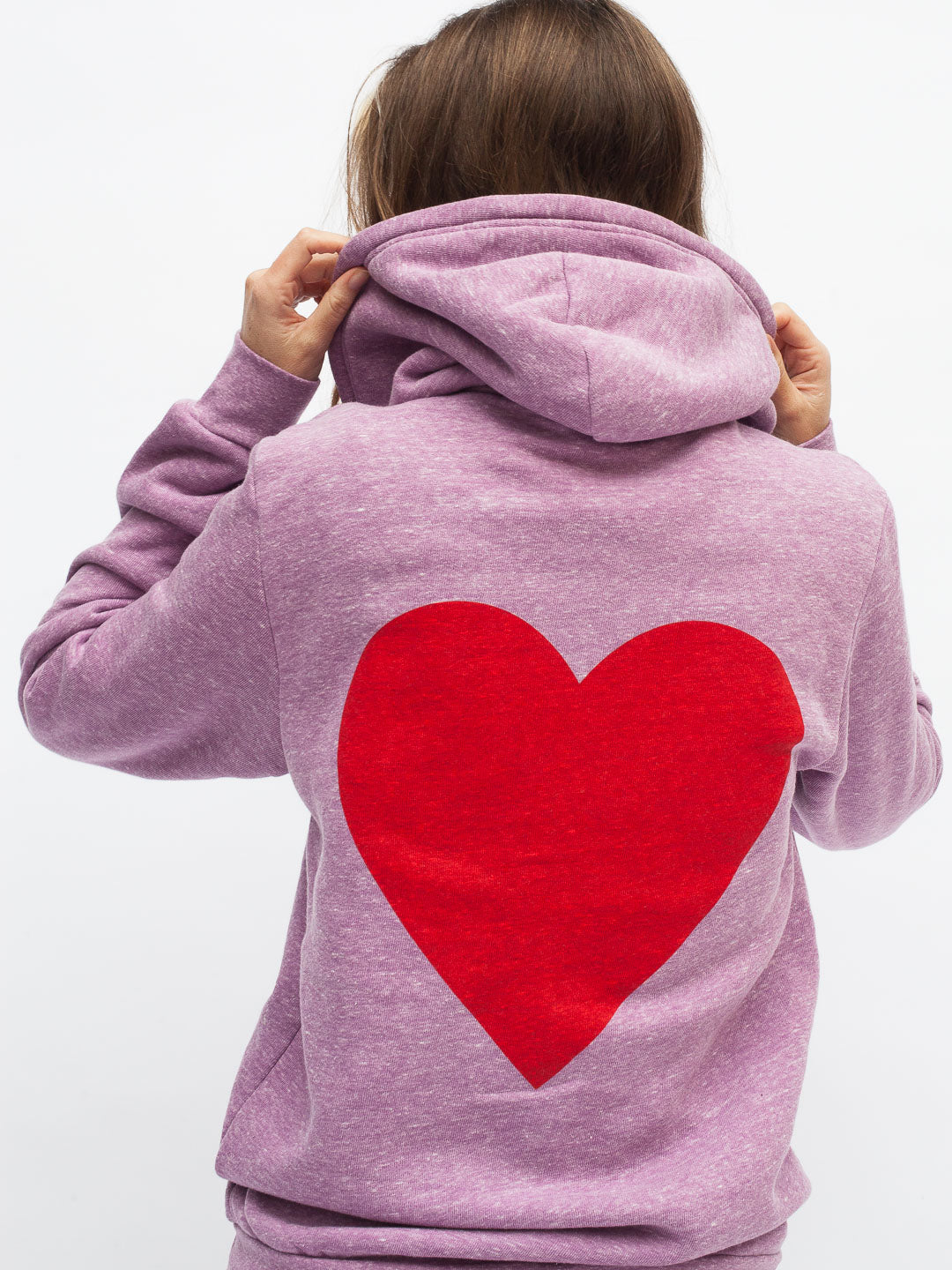 Person wearing a purple hoodie with a red heart on the back against a white background