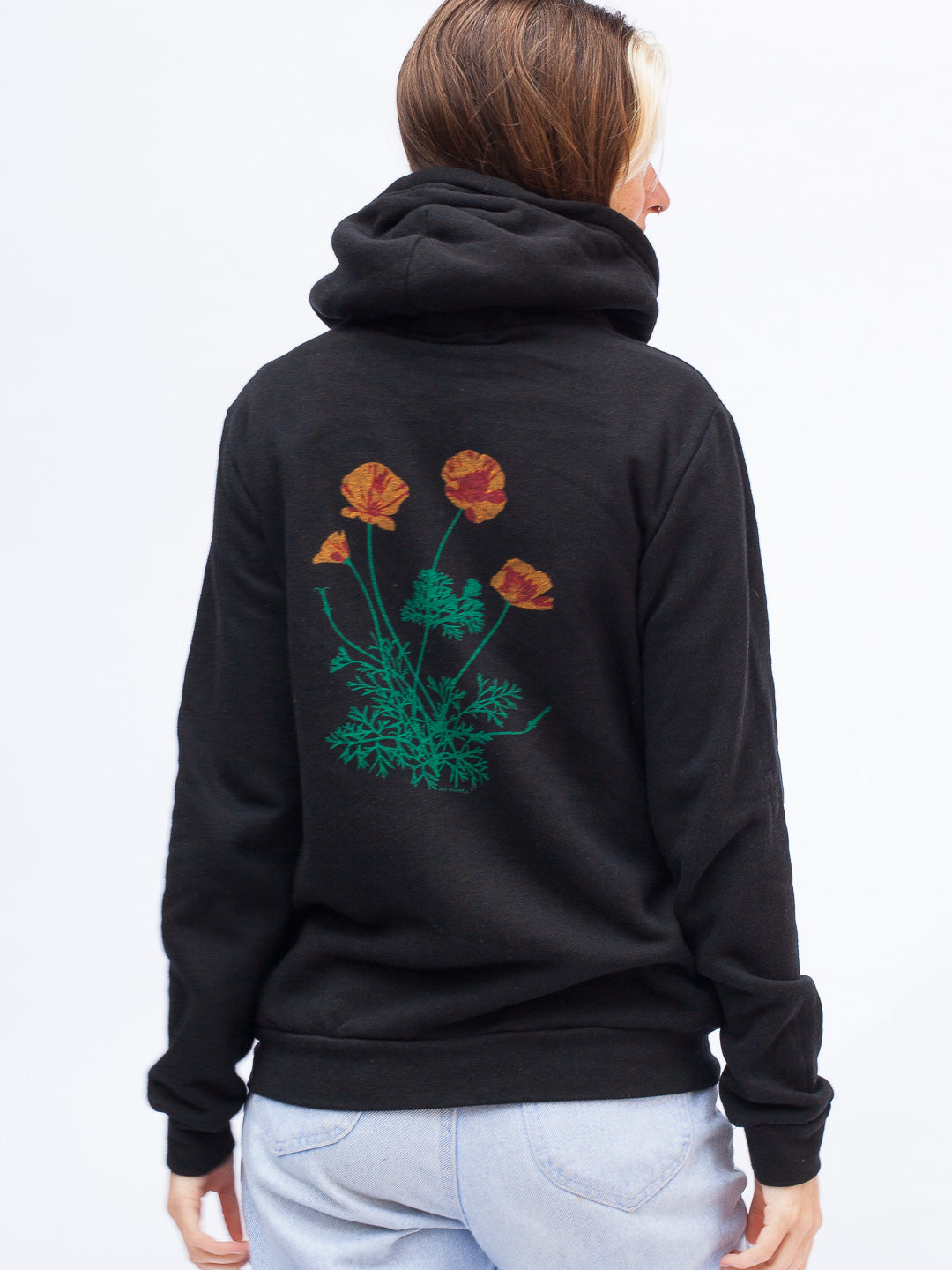 Woman wearing a black hoodie with a colorful logo on a white background