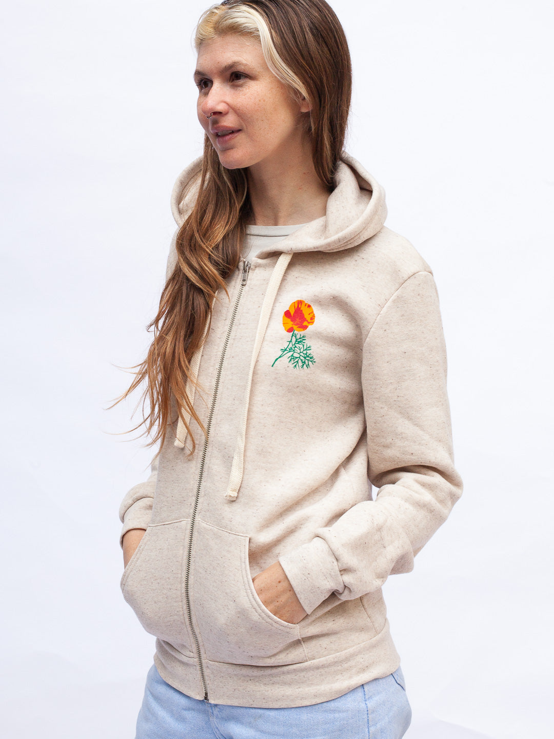 Woman wearing a beige hoodie with a colorful flower design on a white background