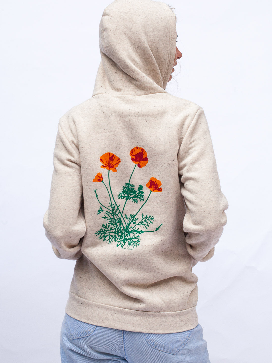 Person wearing a beige hoodie with a floral design on the back against a white background