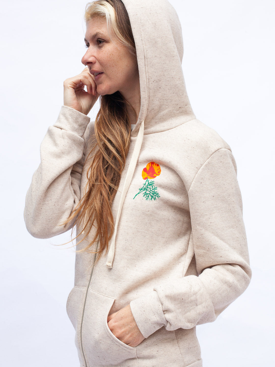 Woman wearing a beige hoodie with a floral design on a white background