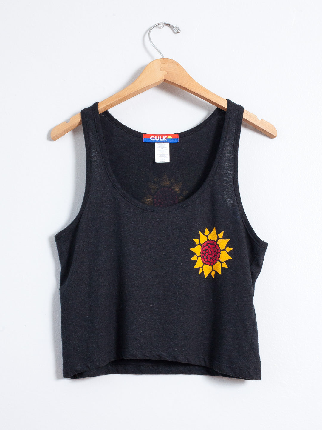 Black tank top with a sunflower design on a hanger against a white background