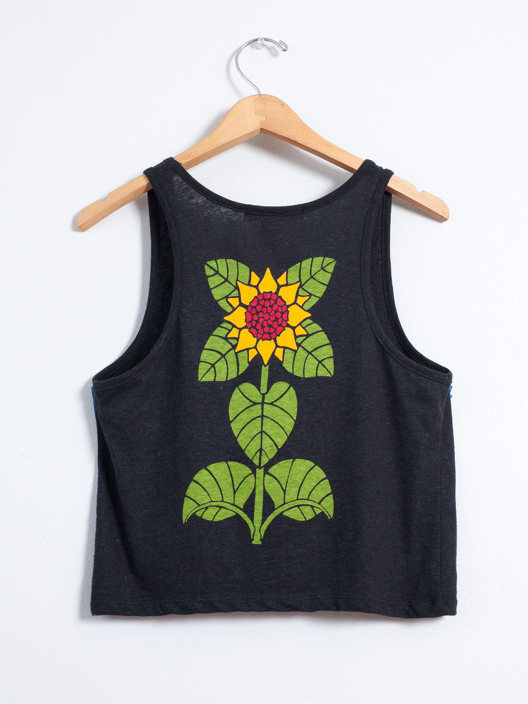 Black tank top with a sunflower design on a hanger against a white background