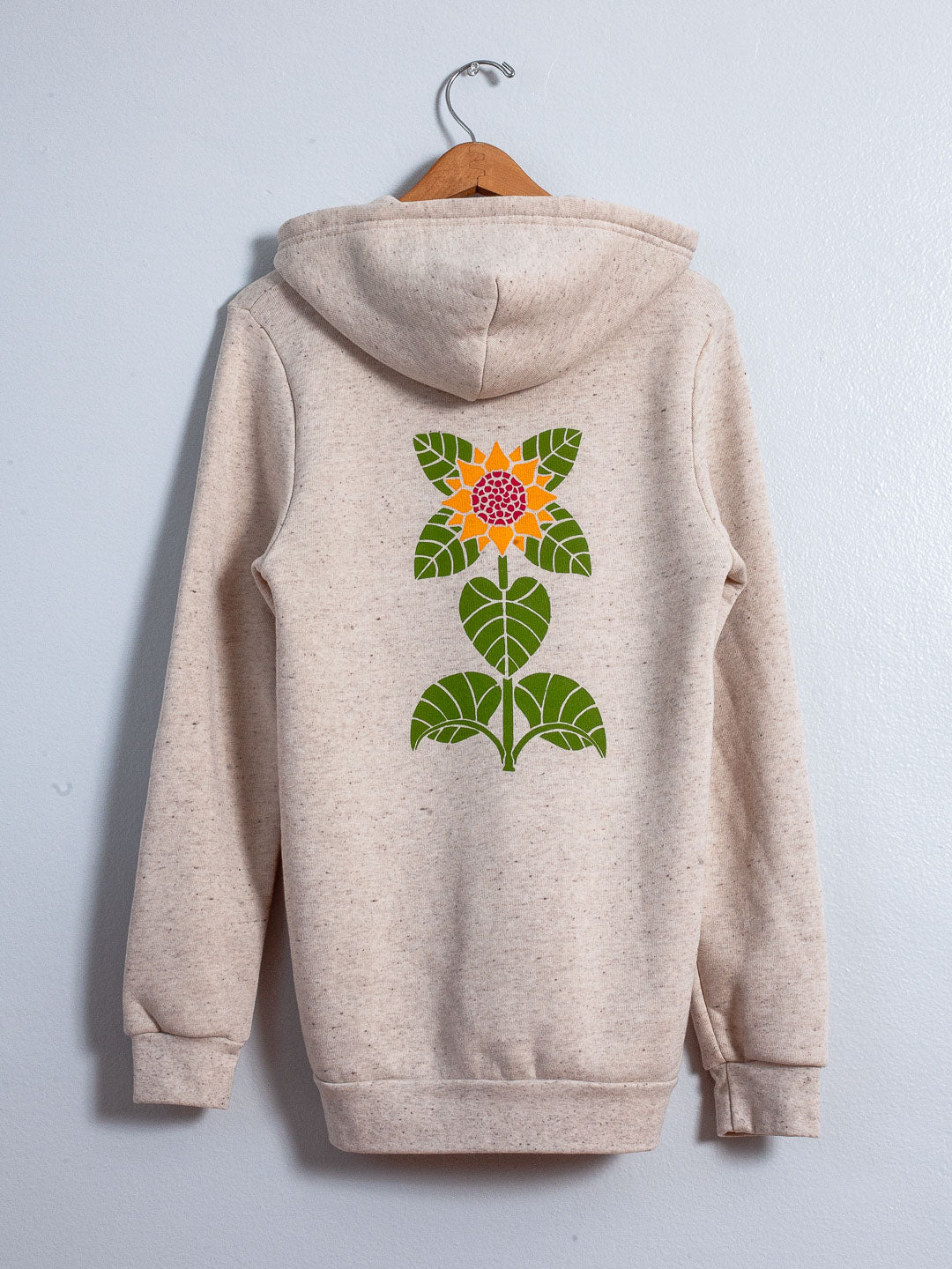 Beige hoodie with a sunflower design on a hanger against a light gray background